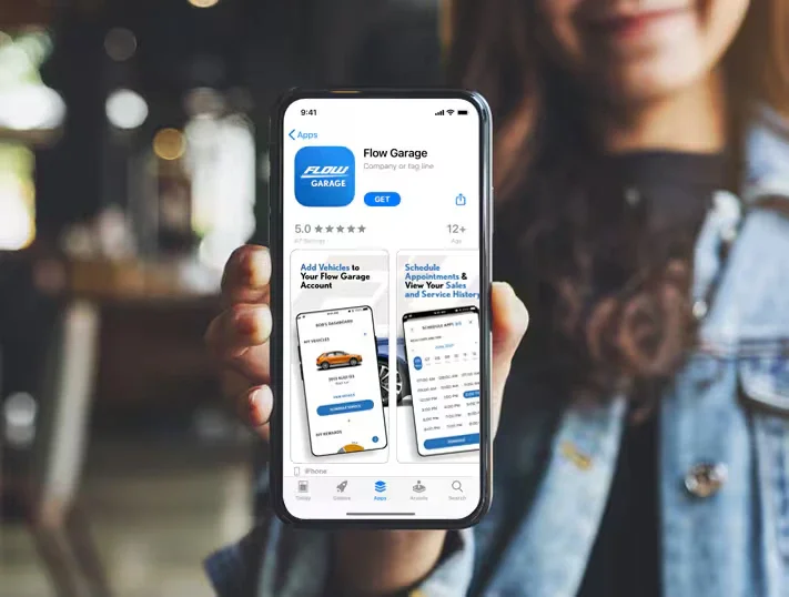 A person holds a phone displaying the Flow Garage app store page and screenshots of its vehicle management features.