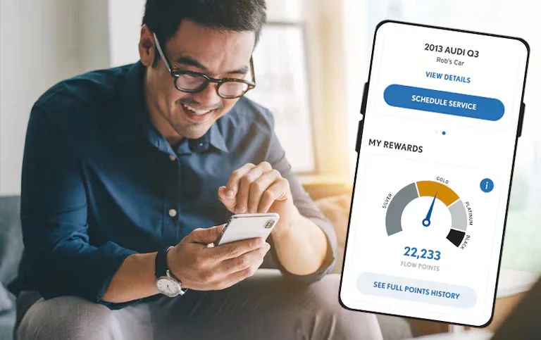 Man smiling while looking at?? phone, with a digital phone overlay showing 'Schedule Service' and 'My Rewards.'